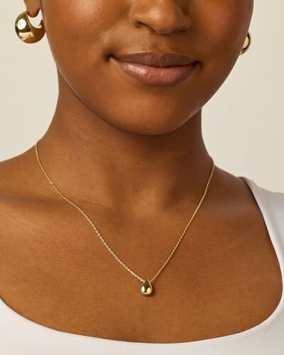 Close-up of a person wearing gold earrings and a necklace.